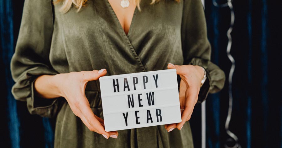 woman holding a sign that says happy new year